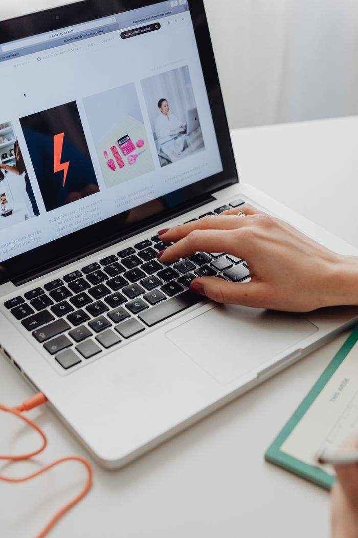 who-we-are Close-up of hand with manicured nails browsing online store on laptop.